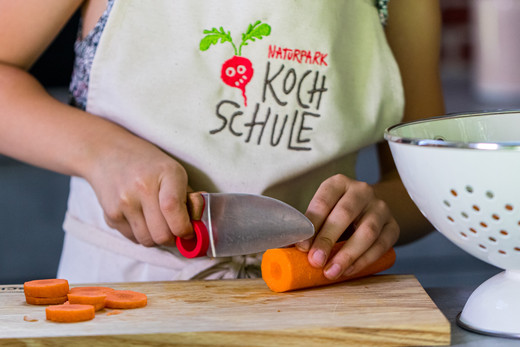 Kind beim Schneiden einer Möhre