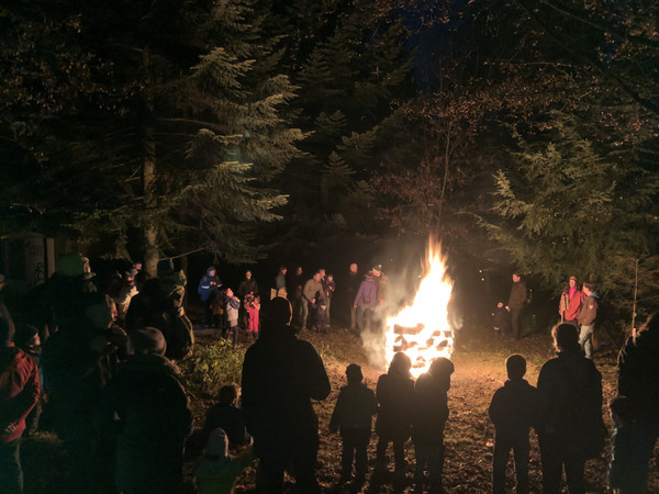 Menschen stehen im Wald um das Nikolausfeuer herum.