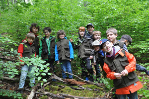 Eine Gruppe Kinder mit Natur-Entdecker-Westen im Wald